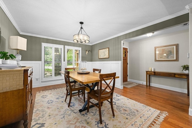 2400 Muirfield Cir, Austin, TX 78747 - dining space featuring ornamental molding, wood finished floors, a wainscoted wall, a chandelier, and a decorative wall