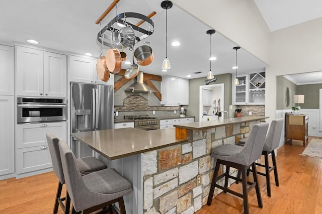 2400 Muirfield Cir, Austin, TX 78747 - kitchen with appliances with stainless steel finishes, wall chimney exhaust hood, backsplash, a kitchen bar, and recessed lighting