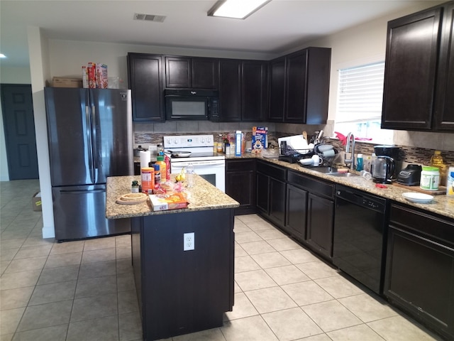 11540 Arbroath Ln, Austin, TX 78754 - kitchen featuring black appliances, light stone counters, a kitchen island, light tile patterned floors, and backsplash