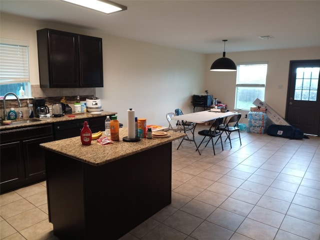 11540 Arbroath Ln, Austin, TX 78754 - kitchen featuring light tile patterned floors, a center island, light stone counters, hanging light fixtures, and dark cabinetry