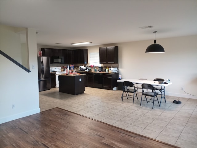 11540 Arbroath Ln, Austin, TX 78754 - kitchen featuring black appliances, a kitchen island, dark cabinets, hanging light fixtures, and light tile patterned floors