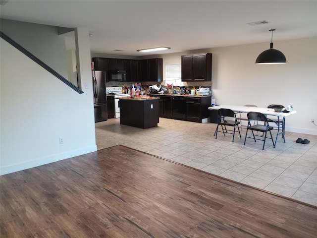 11540 Arbroath Ln, Austin, TX 78754 - kitchen featuring black appliances, a kitchen island, dark cabinetry, decorative light fixtures, and light tile patterned floors