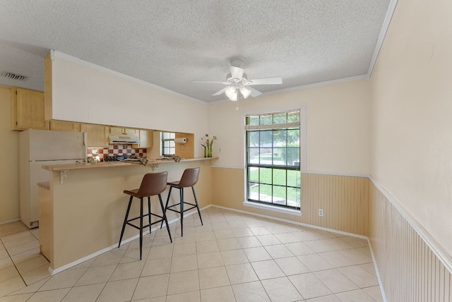 2014 Stagecoach Trl, Temple, TX 76502 - kitchen with freestanding refrigerator, a textured ceiling, a wainscoted wall, a peninsula, and a breakfast bar area