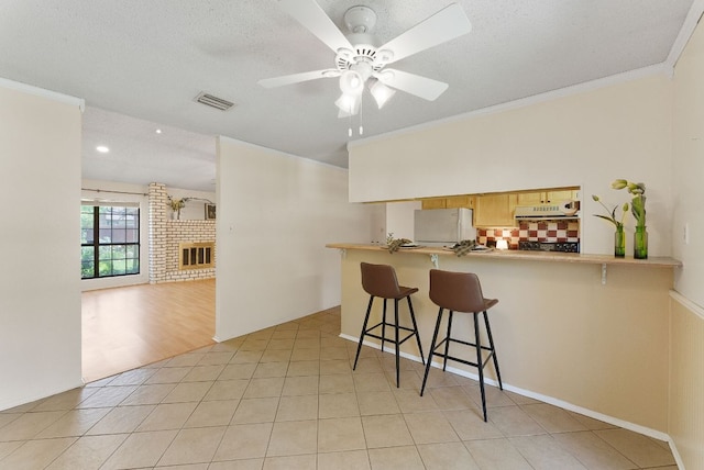 2014 Stagecoach Trl, Temple, TX 76502 - kitchen featuring freestanding refrigerator, a ceiling fan, tasteful backsplash, a breakfast bar area, and ornamental molding