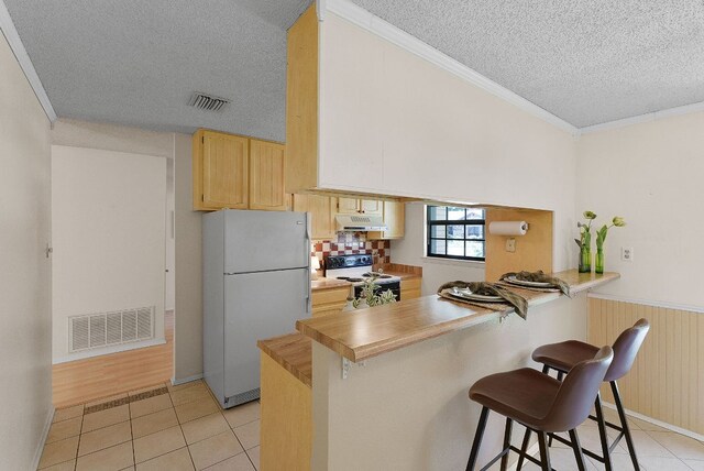 2014 Stagecoach Trl, Temple, TX 76502 - kitchen with white appliances, a textured ceiling, light brown cabinets, light tile patterned floors, and under cabinet range hood