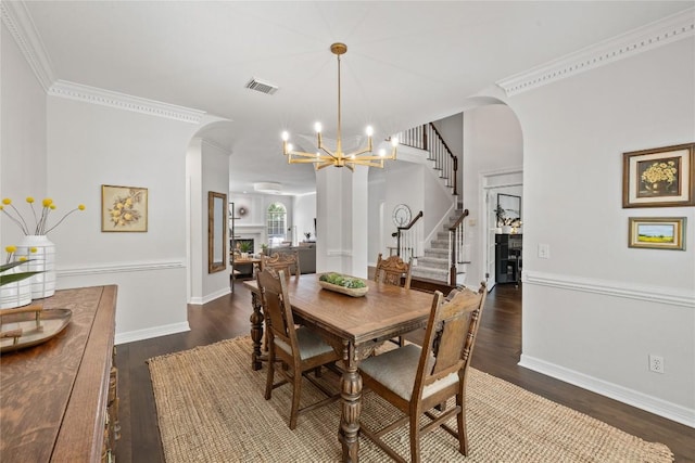 11235 Tracton Ln, Austin, TX 78739 - dining area with arched walkways, dark wood-style floors, a chandelier, stairs, and ornamental molding