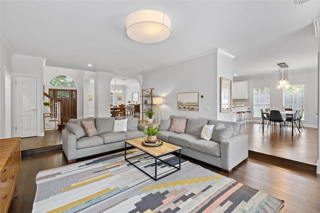 11235 Tracton Ln, Austin, TX 78739 - living room with arched walkways, a chandelier, dark wood-type flooring, crown molding, and stairs