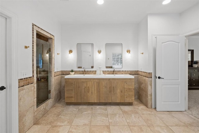 11235 Tracton Ln, Austin, TX 78739 - full bathroom featuring tile walls, double vanity, a shower stall, tile patterned floors, and wainscoting