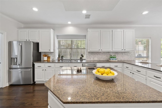 11235 Tracton Ln, Austin, TX 78739 - kitchen with stainless steel fridge, plenty of natural light, dark stone countertops, ornamental molding, and white cabinetry