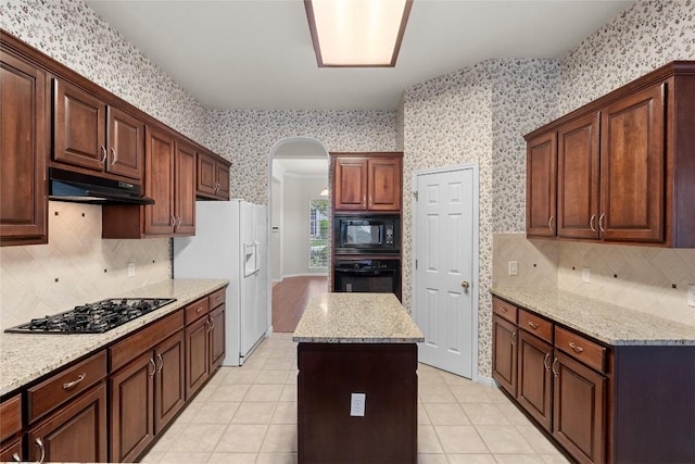 403 Warm Breeze Cv, Austin, TX 78717 - kitchen with wallpapered walls, black appliances, under cabinet range hood, arched walkways, and backsplash