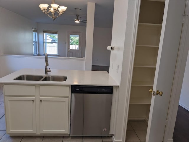 600 Mccarthur Dr, Leander, TX 78641 - kitchen with stainless steel dishwasher, white cabinets, light countertops, light tile patterned flooring, and decorative light fixtures