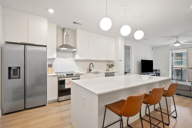 1701 Simond Ave Unit 305, Austin, TX 78723 - kitchen with stainless steel appliances, wall chimney exhaust hood, white cabinetry, light wood finished floors, and tasteful backsplash
