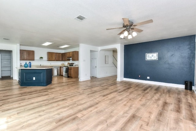 1401 Balsam Way, Round Rock, TX 78665 - unfurnished living room featuring a ceiling fan, light wood finished floors, and arched walkways
