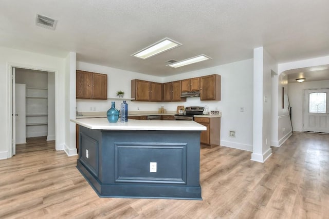 1401 Balsam Way, Round Rock, TX 78665 - kitchen featuring stainless steel range with electric cooktop, light countertops, under cabinet range hood, light wood-type flooring, and arched walkways