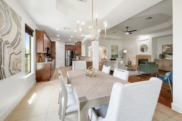 102 Rivulet Ln, Austin, TX 78738 - dining area featuring a raised ceiling, arched walkways, a tiled fireplace, light tile patterned floors, and a ceiling fan
