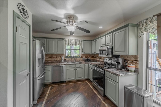 11811 Arabian Trl, Austin, TX 78759 - kitchen with stainless steel appliances, gray cabinetry, decorative backsplash, a ceiling fan, and stone countertops