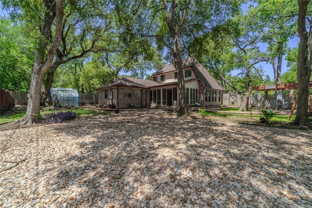 11811 Arabian Trl, Austin, TX 78759 - rear view of property with an outdoor structure, a greenhouse, and a sunroom