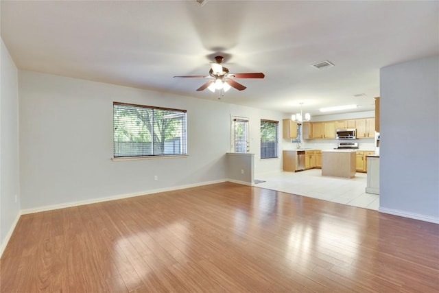 1608 Melibee Trl, Austin, TX 78748 - unfurnished living room with ceiling fan, a chandelier, and light wood-type flooring