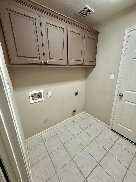 1907 Rutherford Dr, Leander, TX 78641 - laundry area featuring hookup for an electric dryer, cabinet space, washer hookup, and light tile patterned flooring