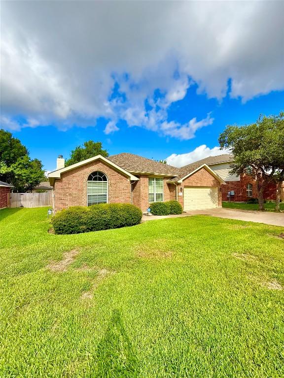 1907 Rutherford Dr, Leander, TX 78641 - ranch-style home featuring a chimney, driveway, an attached garage, and brick siding