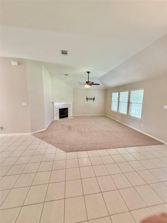 1907 Rutherford Dr, Leander, TX 78641 - unfurnished living room featuring ceiling fan, light colored carpet, vaulted ceiling, a fireplace, and light tile patterned floors