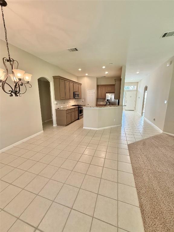 1907 Rutherford Dr, Leander, TX 78641 - kitchen with arched walkways, appliances with stainless steel finishes, open floor plan, light tile patterned flooring, and a chandelier