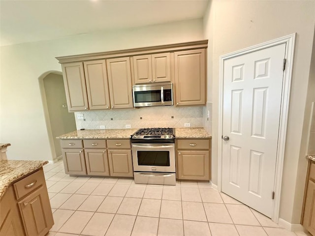 1907 Rutherford Dr, Leander, TX 78641 - kitchen featuring appliances with stainless steel finishes, light tile patterned floors, tasteful backsplash, and arched walkways