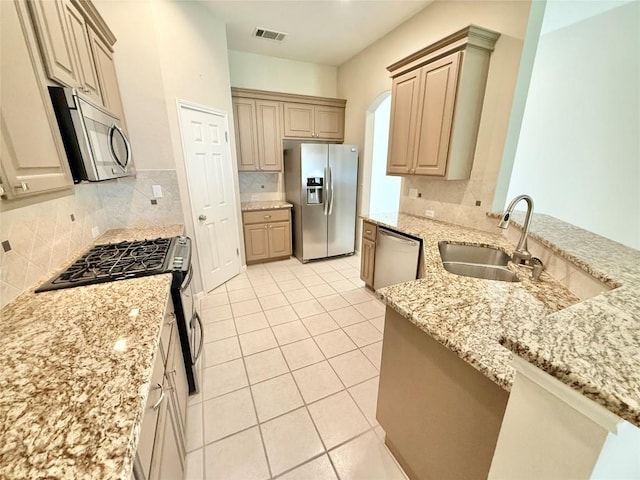 1907 Rutherford Dr, Leander, TX 78641 - kitchen featuring stainless steel appliances, light stone countertops, backsplash, light tile patterned floors, and arched walkways