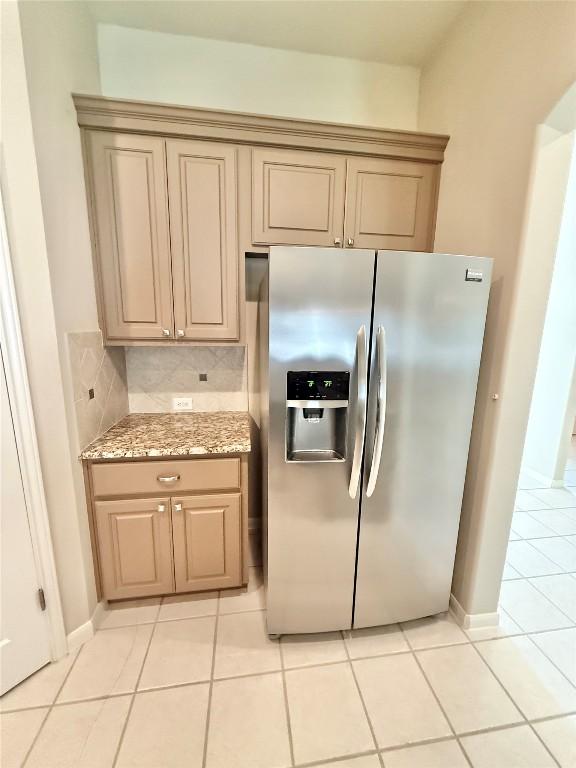 1907 Rutherford Dr, Leander, TX 78641 - kitchen featuring stainless steel fridge, light tile patterned floors, backsplash, and light stone counters