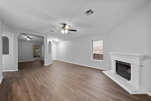 8943 W Hove Loop, Austin, TX 78749 - unfurnished living room with ceiling fan, arched walkways, a fireplace with raised hearth, and dark wood-type flooring
