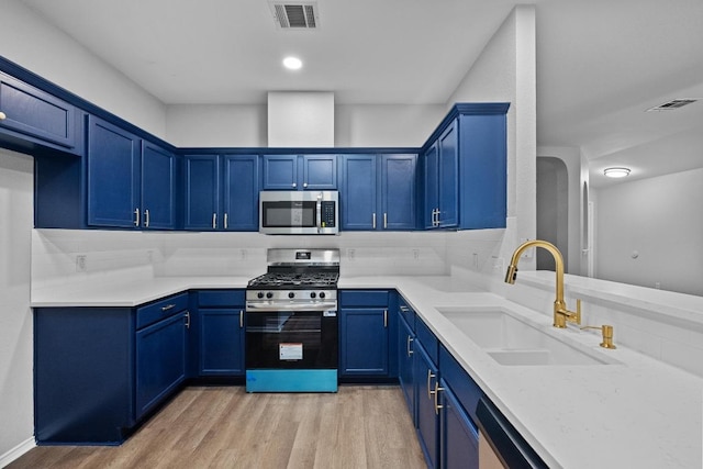 8943 W Hove Loop, Austin, TX 78749 - kitchen featuring appliances with stainless steel finishes, blue cabinets, and light wood-style floors