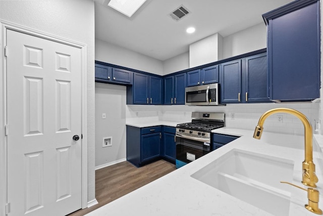 8943 W Hove Loop, Austin, TX 78749 - kitchen with appliances with stainless steel finishes, blue cabinetry, decorative backsplash, light countertops, and wood finished floors