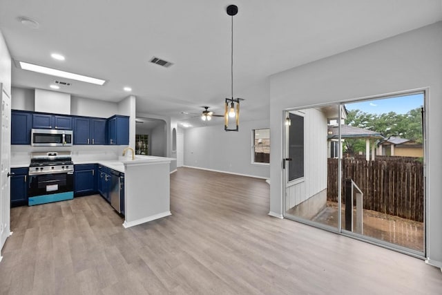 8943 W Hove Loop, Austin, TX 78749 - kitchen with stainless steel appliances, blue cabinetry, a peninsula, ceiling fan, and light wood-type flooring