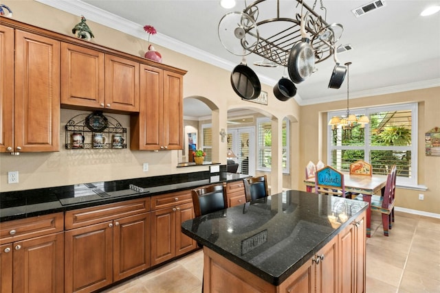 5100 Hadle Cv, Austin, TX 78730 - kitchen featuring black electric stovetop, a chandelier, brown cabinets, light tile patterned flooring, and arched walkways
