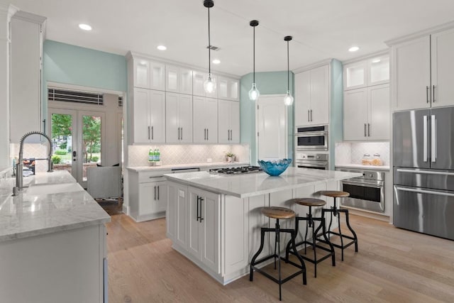 908 Lakewood Hills Ter, Austin, TX 78732 - kitchen featuring stainless steel appliances, white cabinets, decorative backsplash, a center island, and recessed lighting