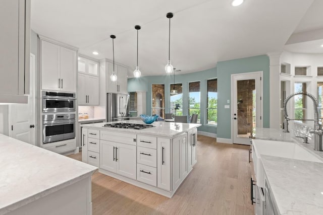 908 Lakewood Hills Ter, Austin, TX 78732 - kitchen featuring recessed lighting, white cabinets, appliances with stainless steel finishes, light wood finished floors, and decorative light fixtures