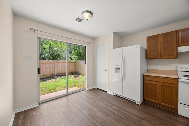 13620 Merseyside Dr, Pflugerville, TX 78660 - kitchen with white appliances, under cabinet range hood, brown cabinets, and dark wood-style flooring