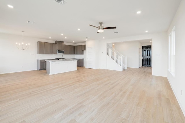 4852 Mozzafiato Ln, Round Rock, TX 78665 - unfurnished living room with recessed lighting, stairs, light wood-type flooring, a chandelier, and a ceiling fan