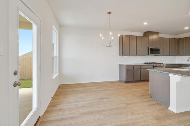 4852 Mozzafiato Ln, Round Rock, TX 78665 - kitchen featuring stainless steel appliances, light wood-style flooring, a chandelier, pendant lighting, and recessed lighting