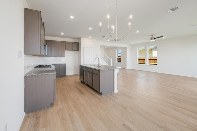 4852 Mozzafiato Ln, Round Rock, TX 78665 - kitchen featuring stainless steel appliances, light wood-style flooring, light stone counters, a chandelier, and open floor plan