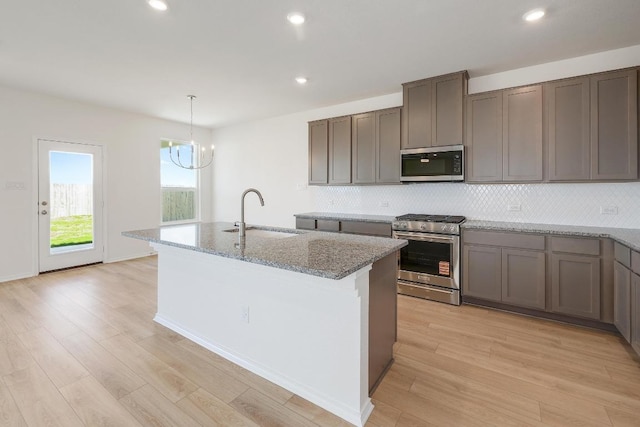 4852 Mozzafiato Ln, Round Rock, TX 78665 - kitchen with stainless steel appliances, decorative backsplash, light wood finished floors, light stone counters, and recessed lighting