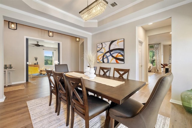 128 Big Sky Cv, Austin, TX 78737 - dining area with light wood-type flooring, ornamental molding, and a tray ceiling