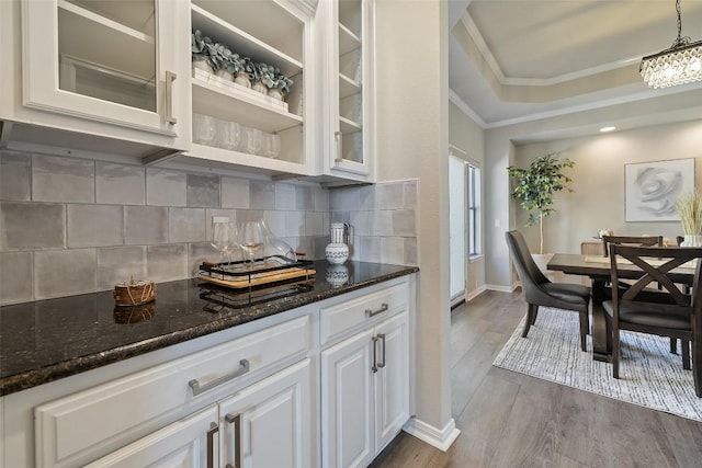 128 Big Sky Cv, Austin, TX 78737 - kitchen featuring crown molding, decorative backsplash, dark wood-type flooring, white cabinets, and glass insert cabinets