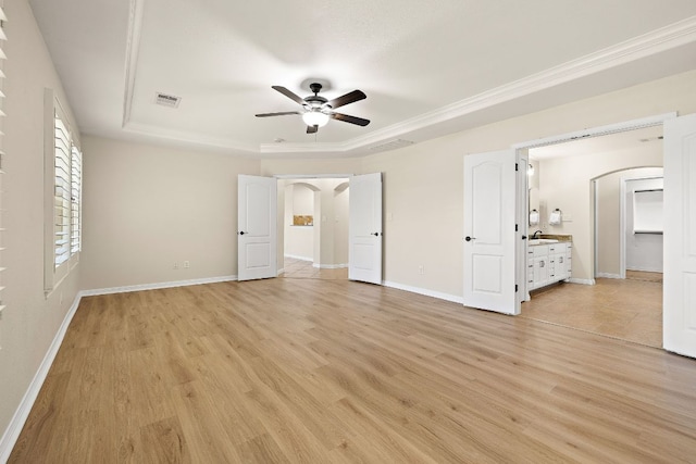 3608 Rockefeller Cv, Lago Vista, TX 78645 - unfurnished bedroom featuring arched walkways, a tray ceiling, light wood-type flooring, and ornamental molding