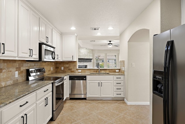 3608 Rockefeller Cv, Lago Vista, TX 78645 - kitchen featuring stainless steel appliances, a ceiling fan, tasteful backsplash, white cabinetry, and light stone counters