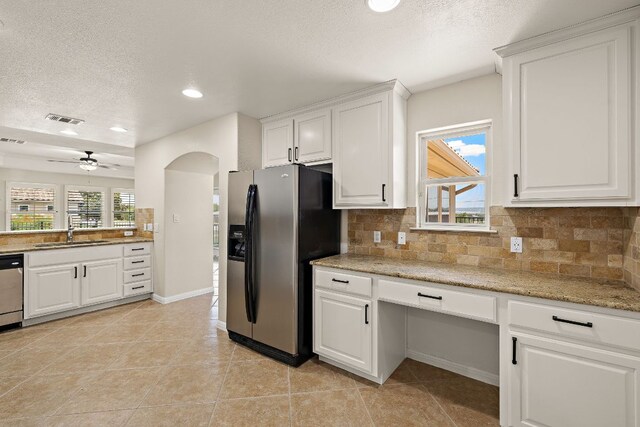 3608 Rockefeller Cv, Lago Vista, TX 78645 - kitchen featuring stainless steel appliances, a textured ceiling, tasteful backsplash, white cabinets, and arched walkways
