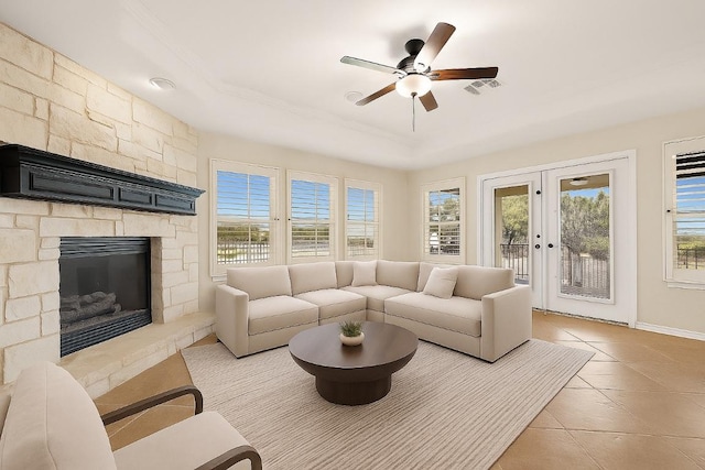 3608 Rockefeller Cv, Lago Vista, TX 78645 - living area featuring a raised ceiling, a ceiling fan, a stone fireplace, tile patterned flooring, and french doors