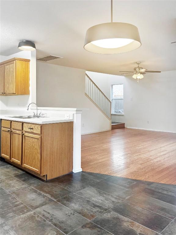 2306 Wilma Rudolph Rd, Austin, TX 78748 - kitchen featuring open floor plan, a ceiling fan, light countertops, a peninsula, and dark wood-type flooring