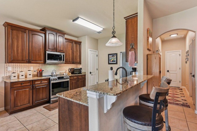 157 Old Firetower Rd, Bastrop, TX 78602 - kitchen featuring stainless steel appliances, arched walkways, light tile patterned floors, and a kitchen bar