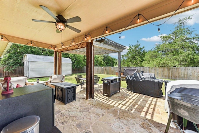 157 Old Firetower Rd, Bastrop, TX 78602 - fenced backyard with an outdoor living space with a fire pit, a storage shed, a patio, area for grilling, and a ceiling fan